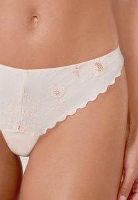 Culotte rose pâle brodée avec une taille en dentelle, présentant des motifs floraux et une finition lisse en tissu doux.