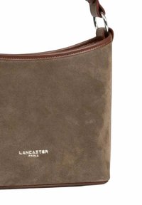 Borsa a mano in suede marrone con una texture liscia, dettagli in pelle marrone e hardware in argento. Il logo "Lancaster Paris" è impresso sul davanti.
