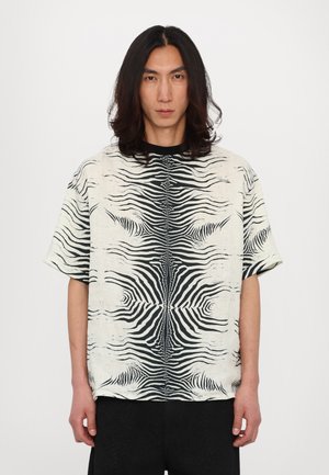 Short-sleeve shirt featuring a black and white zebra stripe pattern, made of textured fabric with a crew neckline and relaxed fit.