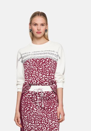 Sweatshirt mit weißem Oberteil und weinrotem Unterteil, das einen weißen Leopardenmuster aufweist. Das Material wirkt weich, mit lockerem Schnitt und Seitentaschen.