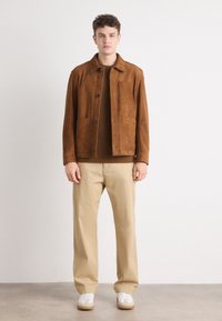 Brown suede jacket with pockets, brown sweater underneath, beige pants, and white sneakers with beige soles. Simple, classic design.