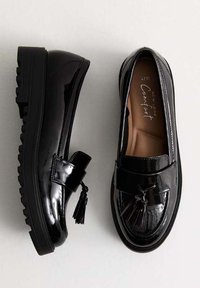 Czarne lakierowane loafersy z chunky podeszwą, z akcentem frędzli i gładkim, błyszczącym wykończeniem. Wewnątrz beżowa wyściełana wkładka.
