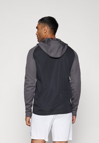 Hættepullover i en mørkegrå og sort farveskema, med lange ærmer og en glat tekstur, i et sporty, tætsiddende design.