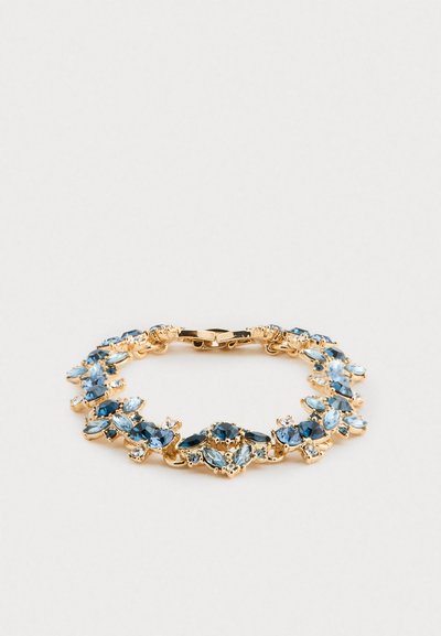Bracelet en or orné de pierres précieuses de diverses formes, bleu foncé et bleu clair, fermé par un fermoir sur fond blanc.