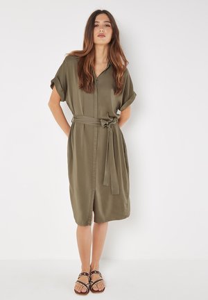 Robe chemise vert olive avec des manches courtes retroussées, ceinture à la taille et fermeture à boutons à l'avant. Tissu lisse avec une coupe décontractée.