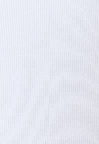 Bílá žebrovaná tkanina s hladkým povrchem, s vertikálními pruhy. Materiál vypadá lehce a elasticky.