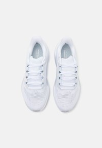 Paire de chaussures de course blanches Nike en tissu mesh avec lacets vue de dessus sur un fond clair.