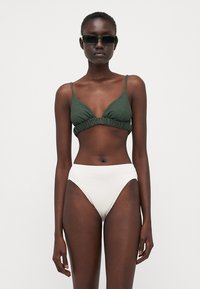 Top bikini verde con texture e dettagli arricciati, abbinato a un fondo bikini bianco alto in vita con texture. Design minimalista, senza motivi visibili.