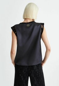 Top in satin nero con maniche in pizzo, caratterizzato da un colletto rotondo e un discreto logo sul retro; texture liscia con vestibilità comoda.