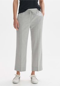 Pantalons larges gris clair en tissu texturé avec une taille élastique et un cordon de serrage. Associés à des baskets blanches.