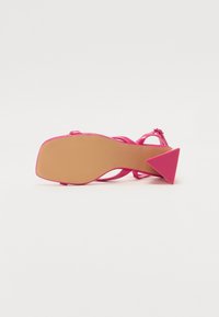 Rosa hæl sandal med en trekantet, teksturert hæl og tynne stropper. Den glatte overflaten har en blank finish som fremhever den livlige fargen.