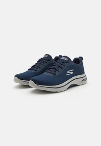 Sneaker a rete blu con suole grigie, dotate di linguetta imbottita, lacci e branding minimale di lato. Design leggero e traspirante.