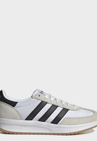 Biało-beżowy sneaker Adidas z czarnymi paskami, wiązany na sznurówki, z wyściełaną podeszwą i oznaczeniem "Cloudfoam" po boku.