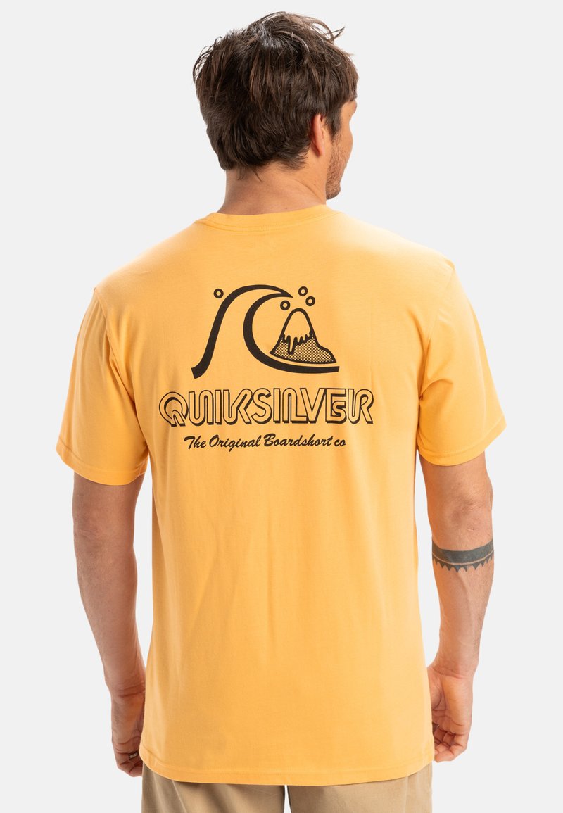 Yellow cotton t-shirt featuring a black graphic of a wave and mountain with "QUIKSILVER" text below. Short sleeves and a relaxed fit.