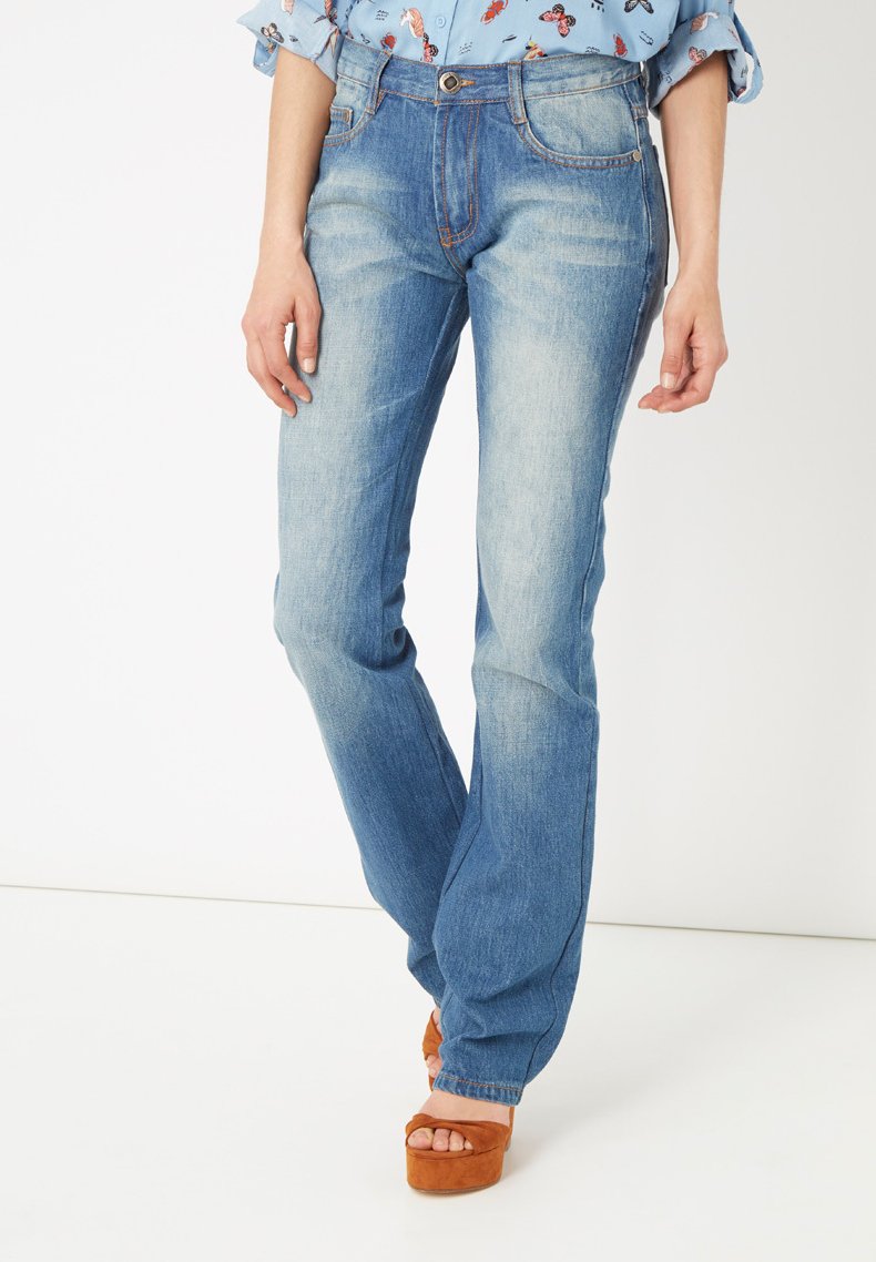 Jeans de mezclilla azul claro con efecto desvanecido, diseño de cinco bolsillos y corte recto, combinados con zapatos de plataforma marrones.