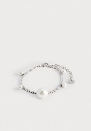 Srebrna bransoletka z dużą centralną perłą i mniejszymi perłami, zdobiona przezroczystymi kryształkami w delikatnym wzorze łańcuszka.