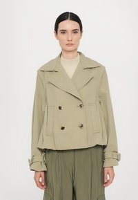 Khaki dvouřadý kabát s širokými klopami, knoflíkovými detaily a zkráceným střihem. Texturovaná látka s hladkým povrchem. Dlouhé rukávy s manžetami.