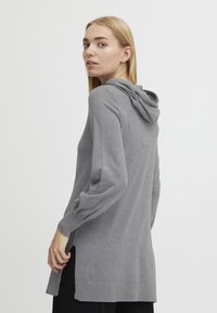 Grauer Kapuzenpulli mit lockerer Passform, langen Ärmeln, seitlichen Schlitzen und einer weichen Textur. Mit Kordelzugkapuze und gerippten Bündchen.