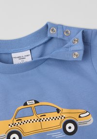 Lyseblå bomulds t-shirt med et gult taxa grafik og sort ternet mønster, korte ærmer og trykknaplukning i halsen.