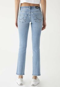 Světle modré rozšířené džíny s vysokým pasem. Mají dvě zadní kapsy s dekorativním stehem a jemně třepení lem. Spárováno s bílými teniskami.