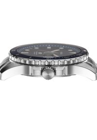 Vista lateral en primer plano de un reloj de pulsera analógico plateado con bisel negro, corona giratoria y marcadores de hora luminosos en la esfera.