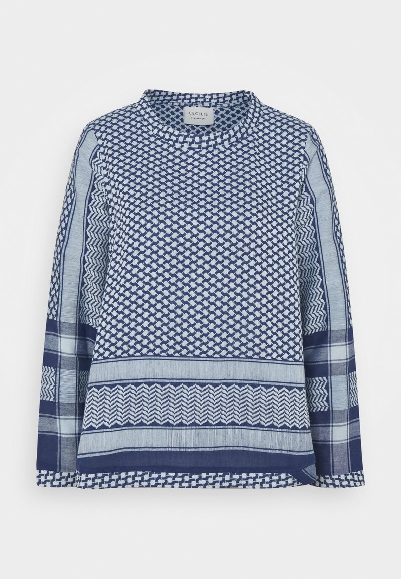 Blouse bleue à motifs avec manches longues, présentant des motifs géométriques variés et des textures différentes, un col rond et une coupe ample.