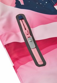 Damejakke med en farvegradient i pink og rød, med en sort kant rundt om en lynlåslomme og et glat, tekstureret stof.