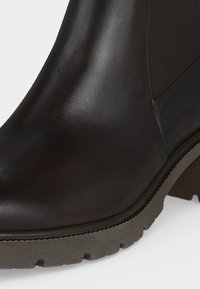 Bottine noire en cuir avec panneau latéral élastique, bout arrondi, semelle épaisse texturée et talon bloc bas.