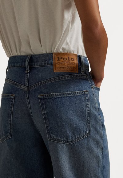 Mørkeblå denimjeans med teksturert overflate. Har et lærmerke med påskriften "Polo" og to baklommer.