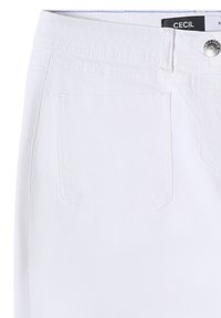 Jean en denim blanc montrant le côté avant supérieur gauche avec poche, passoire de ceinture, fermeture à bouton et étiquette de marque à l'intérieur de la taille.
