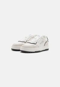 White leather sneakers with gray suede accents, contrasting black rubber sole, round toe, and lace-up closure. Minimalist design.