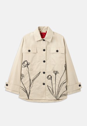 Beige cotton jacket with black floral embroidery on the lower left. Features a front button closure and two chest pockets.