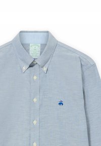 Jasnoniebieska, koszula zapinana na guziki w slim fit. Posiada białe guziki, kołnierzyk oraz małe niebieskie logo na lewej piersi. Wykonana z mieszanki bawełny.