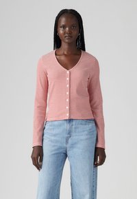 Röd- och vitrandig cardigan med lång ärm, V-ringning, med knappfront, gjord av lätt material, kombinerad med blå jeans.
