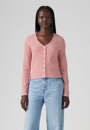 Rot-weiß gestreifter Cardigan, lange Ärmel, V-Ausschnitt, mit Knopfleiste, aus leichtem Stoff, kombiniert mit blauen Jeans.