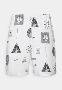 Bílé šortky s černými geometrickými tvary, symboly míru, textem "míra skrze praxi" a logem Nike swoosh po celém materiálu.