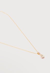 Λεπτό χρυσό κολιέ με αλυσίδα και κρεμαστό στοιχείο σε σχήμα σταγόνας, διαφανές και περιτριγυρισμένο από μικρούς ροζ πολύτιμους λίθους, σε απλό λευκό φόντο.