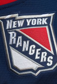 Auf einem dunklen Stoffhintergrund befindet sich ein gesticktes Logo-Patch der New York Rangers, das mit roten, weißen und blauen Farbblöcken gestaltet ist.