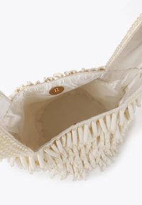Torebka w kolorze kremowym z teksturowaną powierzchnią, ozdobiona białymi koralikami, z gładkim satynowym wnętrzem i zapięciem na magnes.
