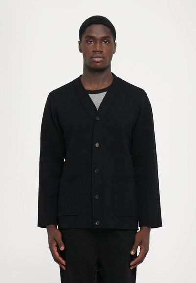 Musthave kašmiirist must kardigan V-kaelusega, esipainutatud nuppudega ja kahe klambriga taskuga. Valmistatud tekstureeritud kangast, millel on pikad varrukad.