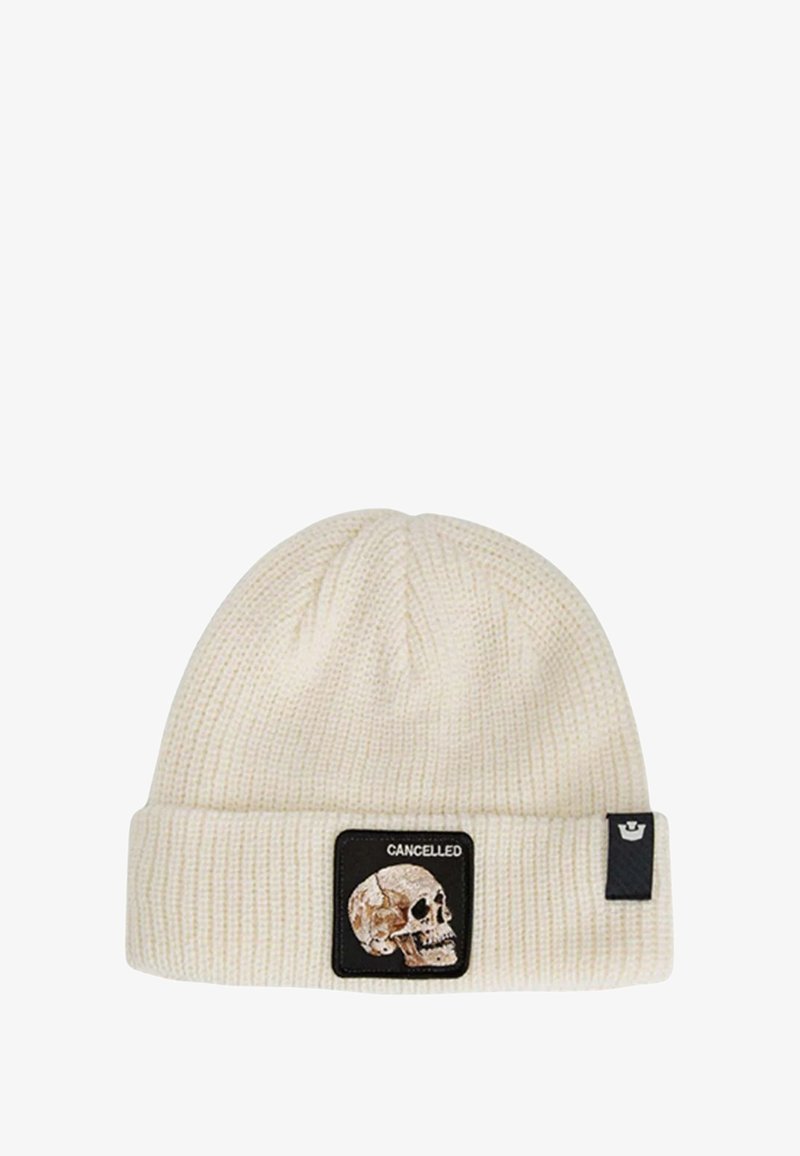 Romige gebreide beanie met ribbelstructuur, voorzien van een zwarte patch met een doodskop en het woord "CANCELLED". Met een omgeslagen rand.