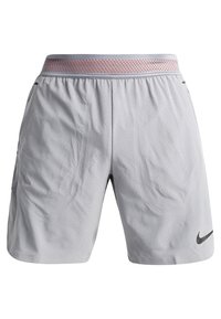 Shorts de sport gris clair perforés avec une ceinture élastique rose et un logo Nike Swoosh noir sur la jambe droite en bas.