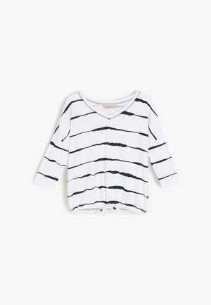 Biała koszula z długim rękawem z nieregularnymi czarnymi poziomymi paskami, dekoltem w serek i regulowanym ściągaczem na dole.