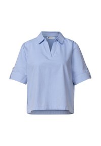 Chemise bleu clair à manches courtes avec col et ouverture en V, manches retroussées maintenues par des pattes boutonnées.