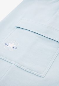 Sweat à capuche bleu clair avec une texture douce, doté d'une poche avant, d'un logo étoile blanche brodé et de détails de couture subtils.