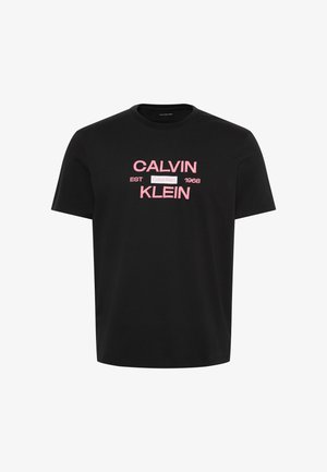 Svart kortermet t-skjorte med rosa tekst "CALVIN KLEIN EST 1968" og en liten hvit firkant med "Calvin Klein" i midten.