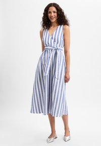 Gestreiftes Wickelkleid in Blau und Weiß mit V-Ausschnitt, einem Bindegürtel in der Taille und Midi-Länge, aus leichtem Stoff. Silberne Schuhe werden präsentiert.