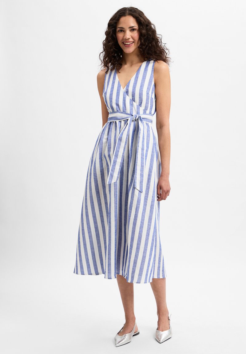 Gestreiftes Wickelkleid in Blau und Weiß mit V-Ausschnitt, einem Bindegürtel in der Taille und Midi-Länge, aus leichtem Stoff. Silberne Schuhe werden präsentiert.
