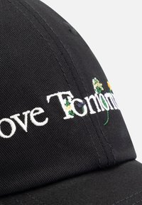 Zwarte katoenen pet met geborduurde tekst en bloemaccenten, met een gestructureerde kroon en een gebogen klep.