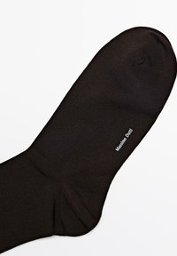 Sort sok i glat strikmateriale med forstærket hæl og tå. Logoet "Massimo Dutti" trykt i hvidt på siden.